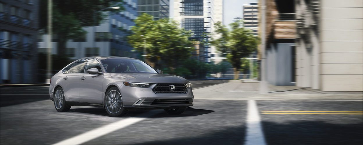 Plan de trois quarts avant d’une Accord grise négociant un virage dans une rue urbaine.