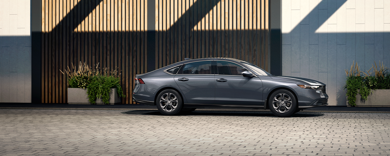 Sideview of grey Accord parked in front of upscale building with wood-slatted wall.