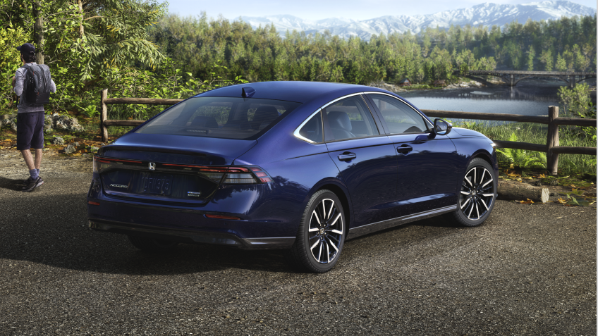 3/4 rear view of a parked blue Accord overseeing a forest and mountains. A hiker walking away from it.