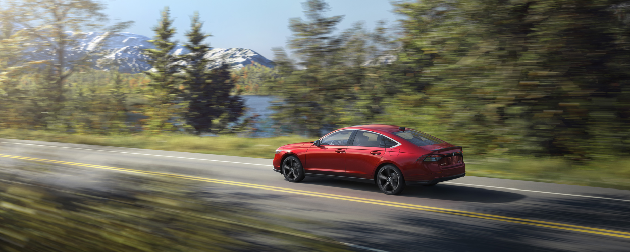 3/4 rear side view of black Accord driving on lakeside highway.