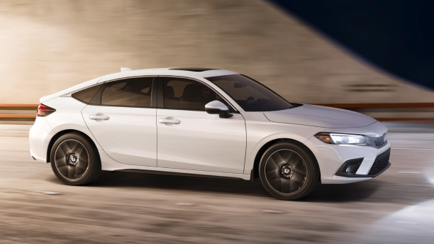 3/4 side front view of white Hatchback exiting a tunnel at night.