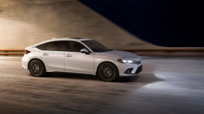 3/4 side front view of white Hatchback exiting a tunnel at night.