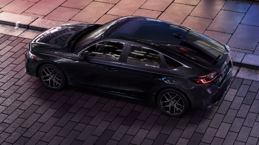 3/4 bird’s eye view of black Hatchback parked on brick city road.