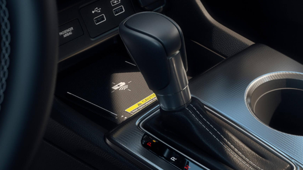 Close up of phone charging on wireless charging pad, in front of the gear shifter. 