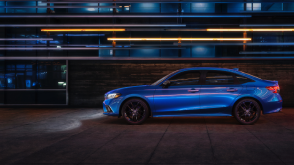 Side view of a parked blue Civic Sedan in a dark warehouse-like space.