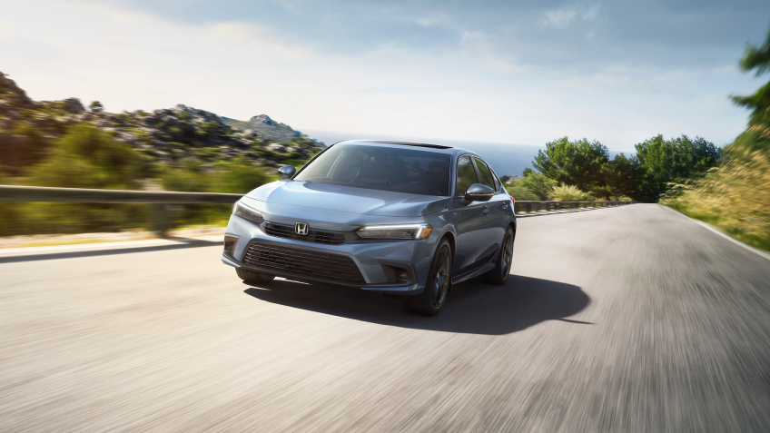 Front view of a grey Civic Sedan driving toward camera on an oceanside highway.