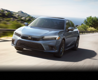 Avant d’une Civic berline grise roulant vers la caméra sur une autoroute côtière.