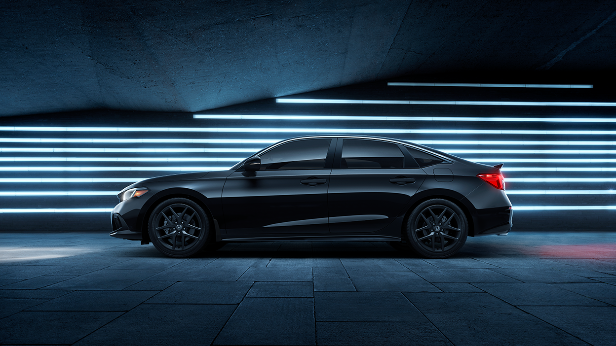 Sideview of black Civic Si parked in front of blue neon lights.