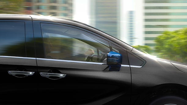 Medium side closeup of black Odyssey driving in city.