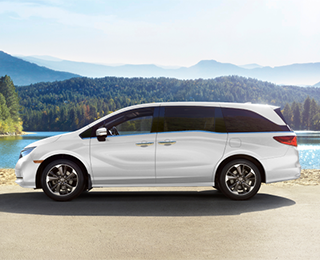 Sideview of white Odyssey, parked lakeside.