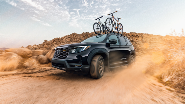 3/4 side front view of black Passport desert off-roading with two bikes on the roof rails.