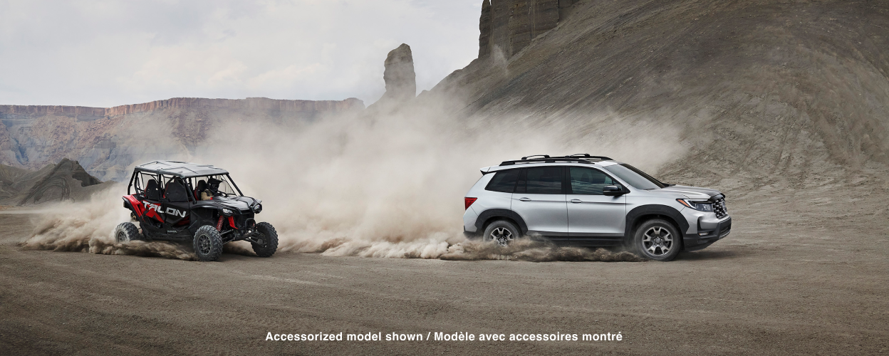Side view of grey Passport off-roading in desert. ATV follows closely behind. 