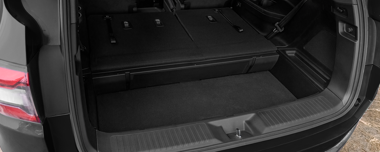View of open tailgate showcasing the on-demand in-trunk storage and the third row seats flat-folded down.