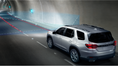 3/4 rear view of grey Pilot in driving in tunnel. Blue sensor lines and waves detect the lane divider lines. 