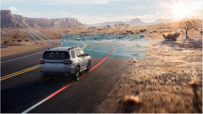 3/4 rear view of grey Pilot taking a curve on a desert highway. Blue sensor waves and lines emit from the front, detecting the white lane line.