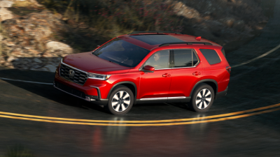 3/4 side view of red Pilot taking a turn on a highway.