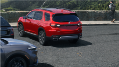 3/4 rear view of red Pilot parked at a tourist lookout point overlooking a green forest valley.