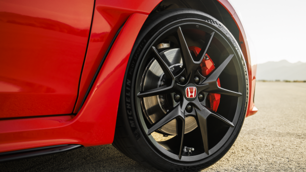 Closeup of black rimmed front wheel on a red Type R in the desert.