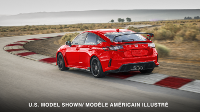 3/4 rear view of red Type R taking a turn on track. 