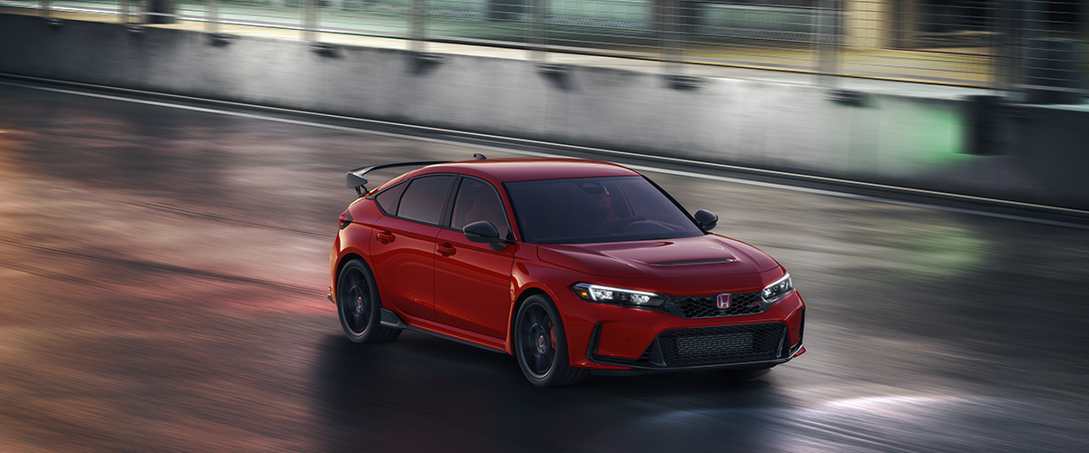 3/4 arial view of a red Type R driving on a race track at night.