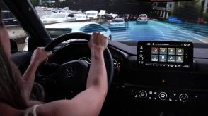 View, out windshield, over driver’s shoulder, showing Type R in traffic. Blue sensor waves emit from the front.